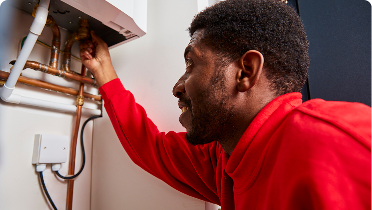 A HomeServe engineer checking heating pipe connections during a boiler service.