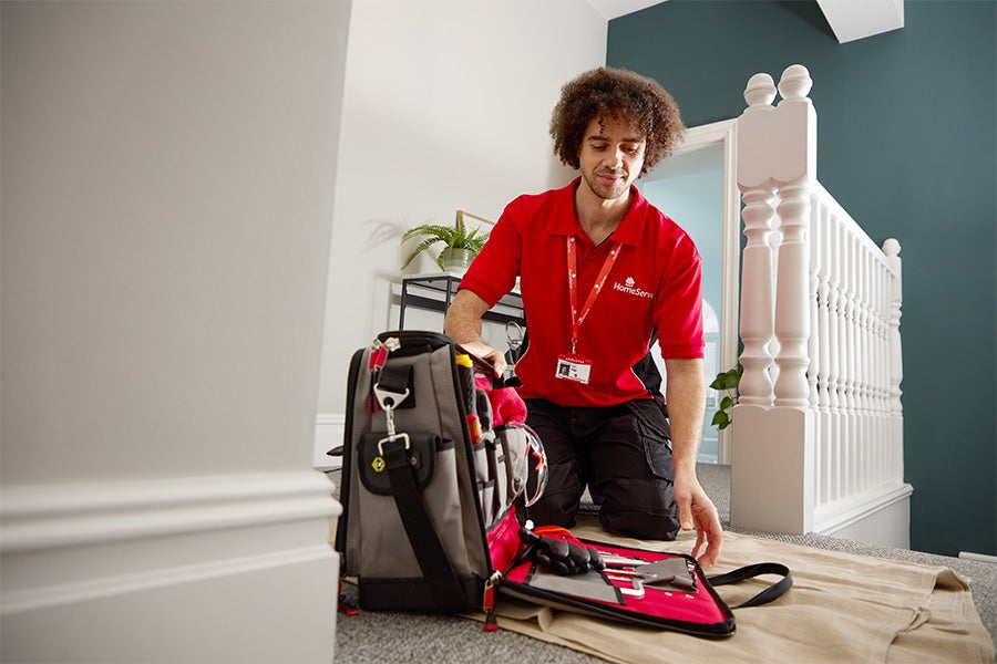 A HomeServe engineer removing tools from a tool bag to start working on a home repair.