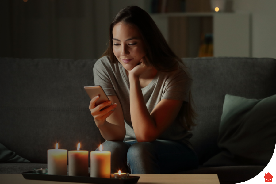 woman sitting in the dark on her mobile phone - What to do in a power cut