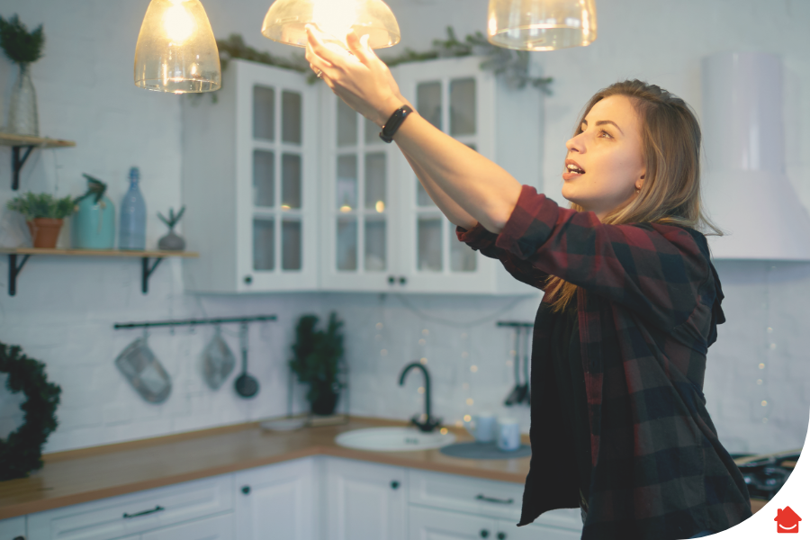 woman changing a light bulb - landlord electrical safety certificate