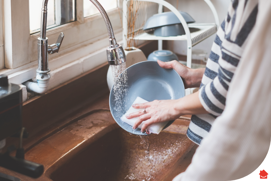 Woman washing the dishes after unclogging her grease-clogged drain.