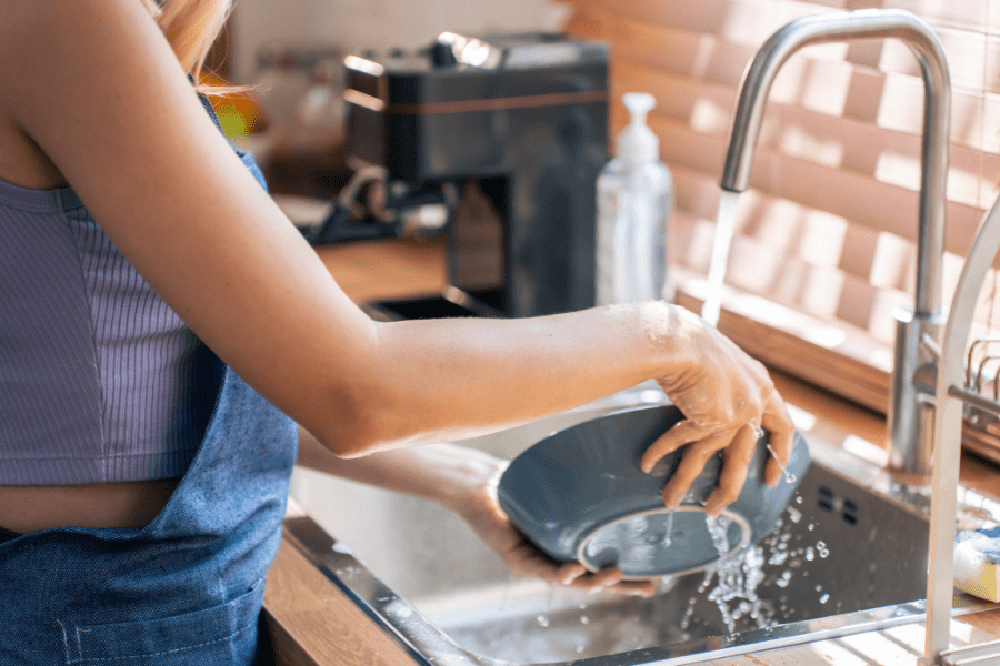 A student washing up in the kitchen sink to prevent kitchen sink smells