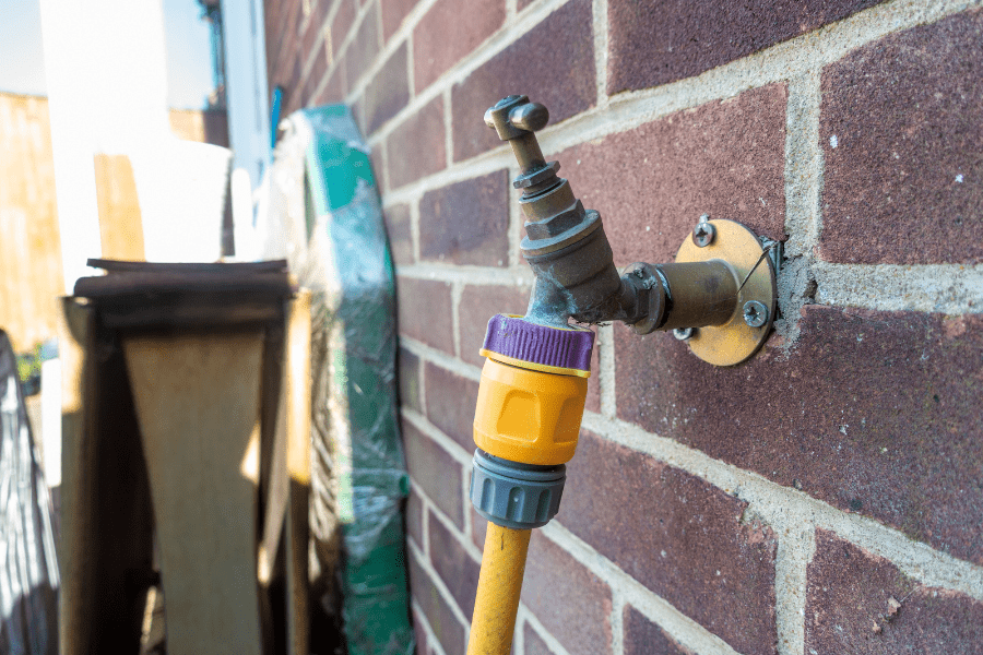 A recently fitted outside tap with a connected hosepipe.