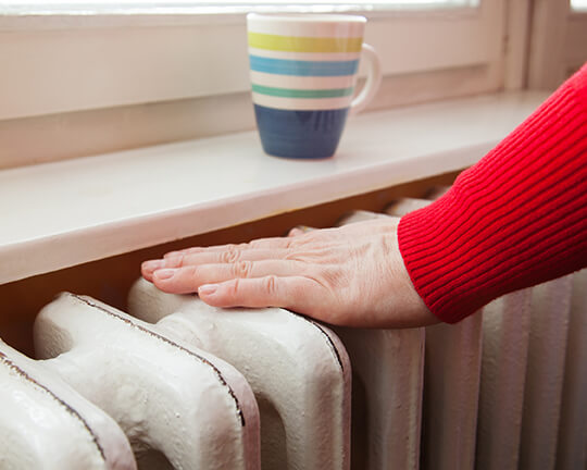 cold radiators - person touching a radiator that is cold at the top