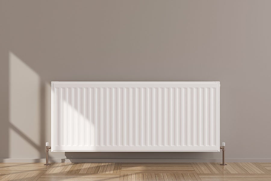 A plumbed radiator in a room with a plain background