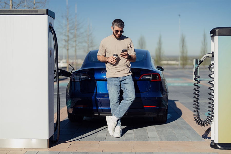 Man waiting for his electric car to charge at a public charging station