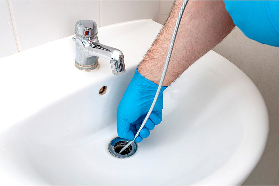 A drain snake being used to unclog a blocked bathroom sink