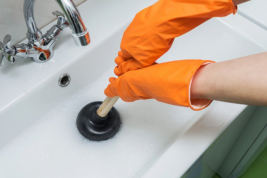 A blocked sink being unblocked using a plunger