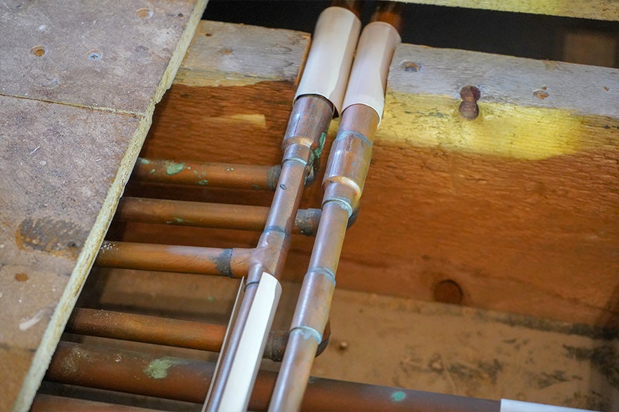 Exposed copper water pipes underneath some floorboards