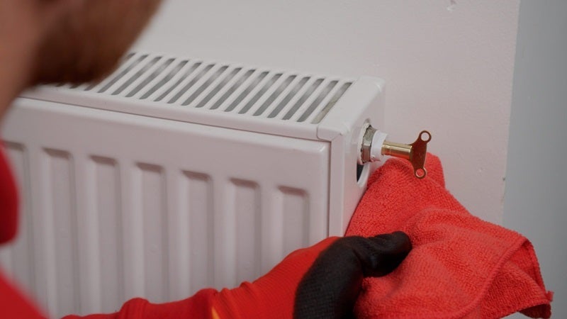 HomeServe engineer bleeding a radiator with a radiator key