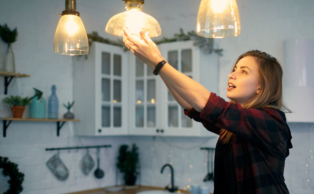 Woman changing light bulb in home